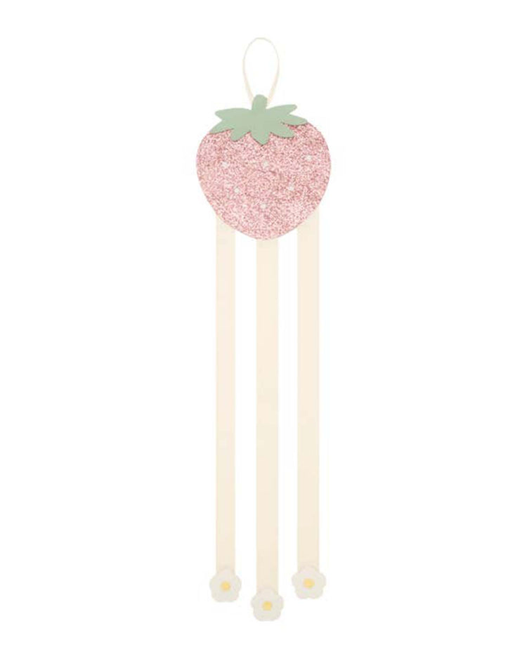 Rockahula kids' sweet strawberry 3 ribbon clip hanger features a charming pink glitter strawberry with green leaves, adorned with three cream ribbons, each ending in a white flower. Perfect for adding an enchanting touch to hair clips or headbands.