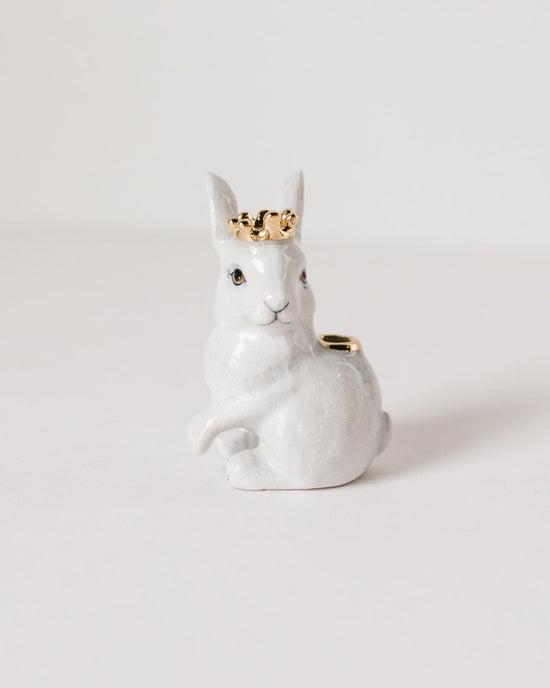 A Camp Hollow royal white rabbit cake topper with a small gold crown, hand-painted, sitting on a plain background.