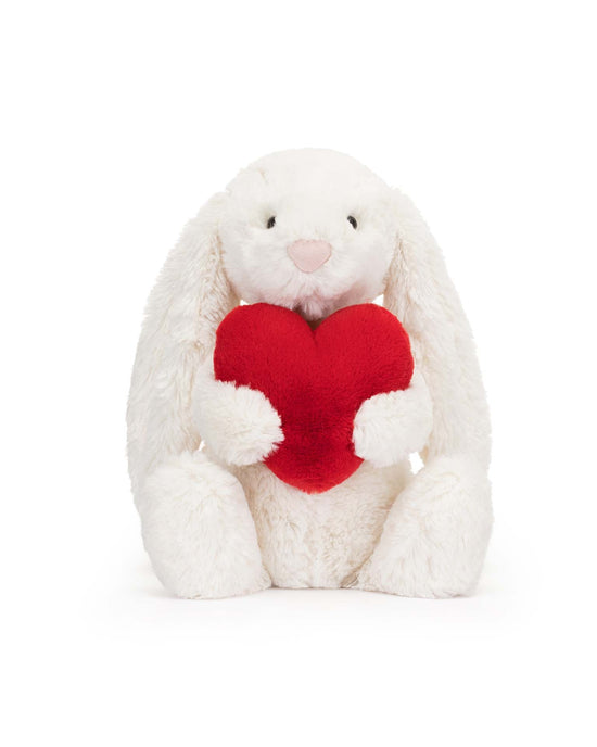 The Jellycat Bashful Red Love Heart Bunny Little, this super soft plush stuffed animal features white fur and clutches a red heart.